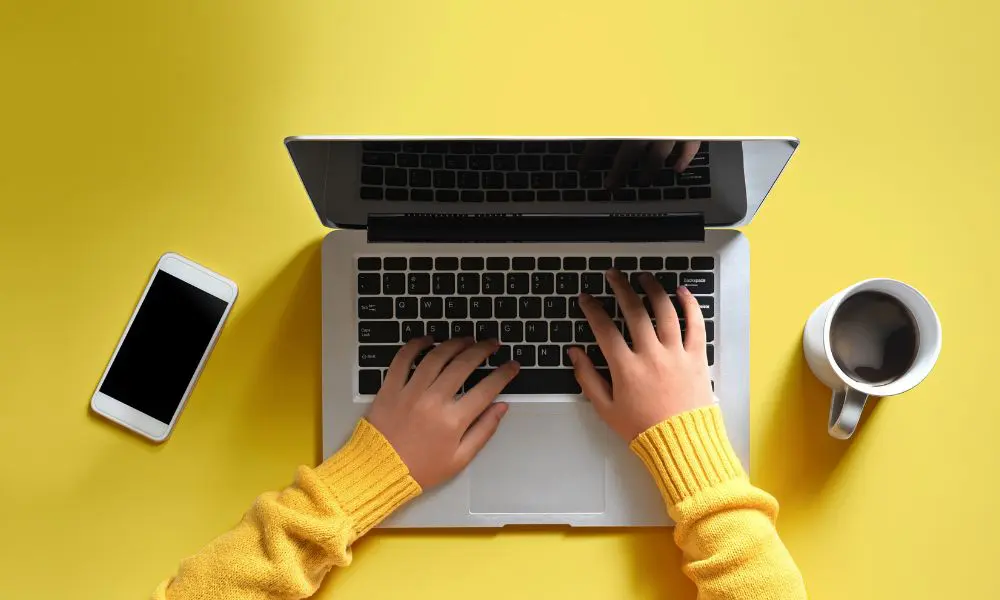 Website Design Pricing - Yellow Background with Person Typing on Laptop - Web Design and SEO Company Limited